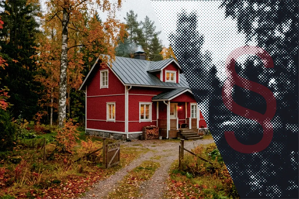 Punainen puutalo syksyisessä metsämaisemassa.
